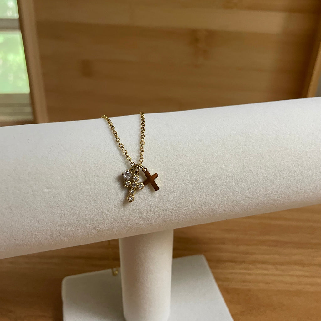Necklace with a cross pendant on a white stand against a wooden background