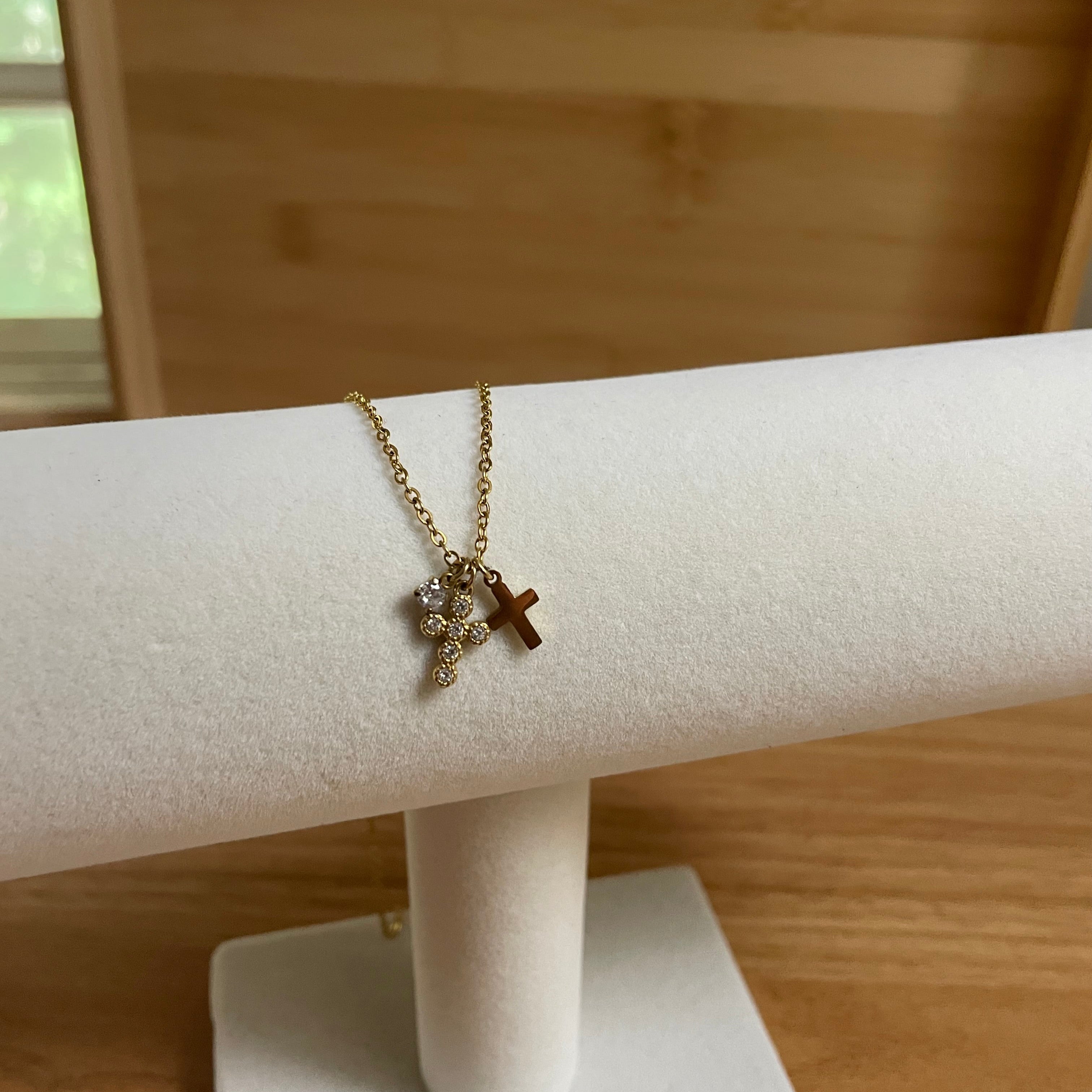 Necklace with a cross pendant on a white stand against a wooden background