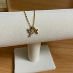 Gold necklace with a cross pendant on a white stand against a wooden background