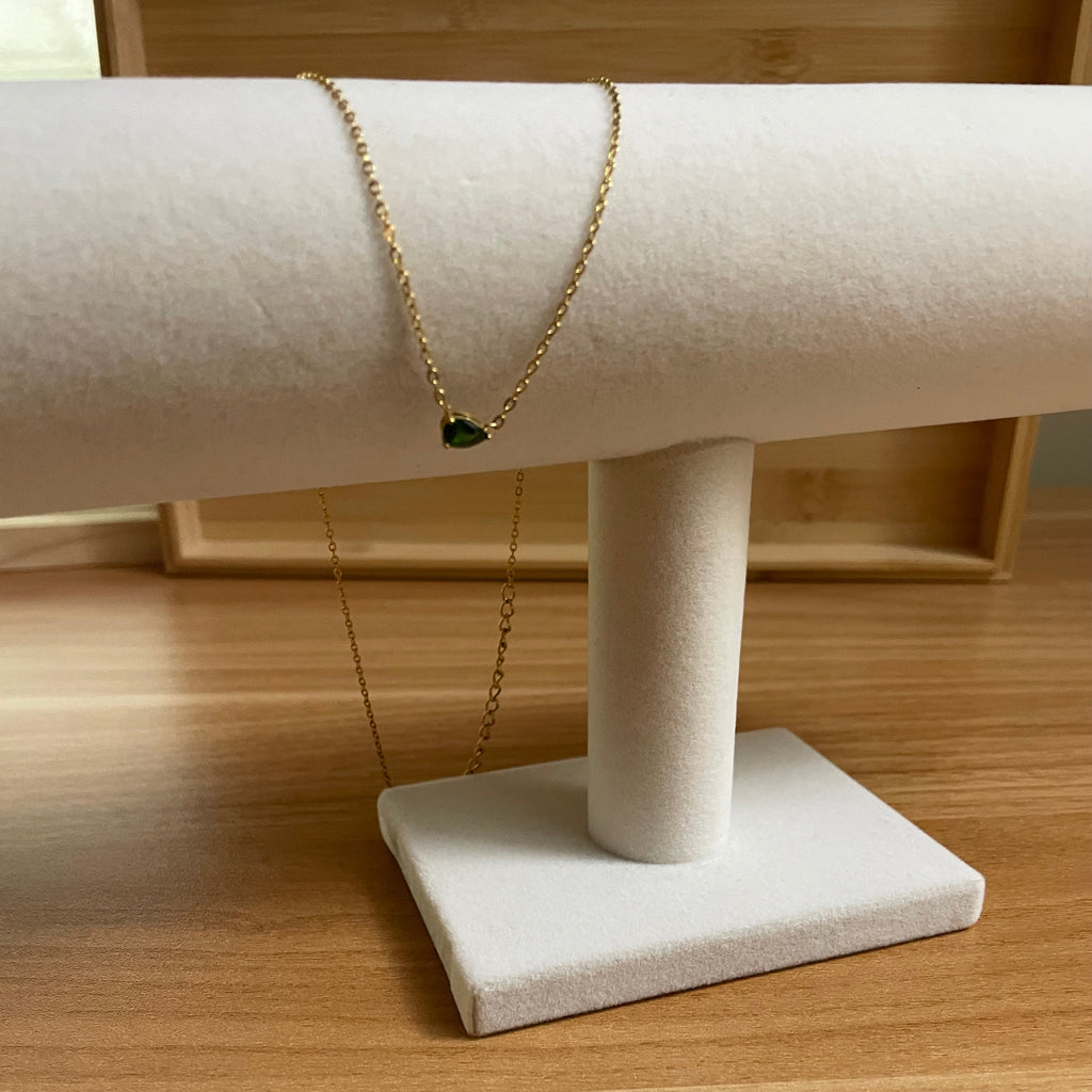 Gold bracelet with a green gemstone on a white mannequin arm against a wooden background