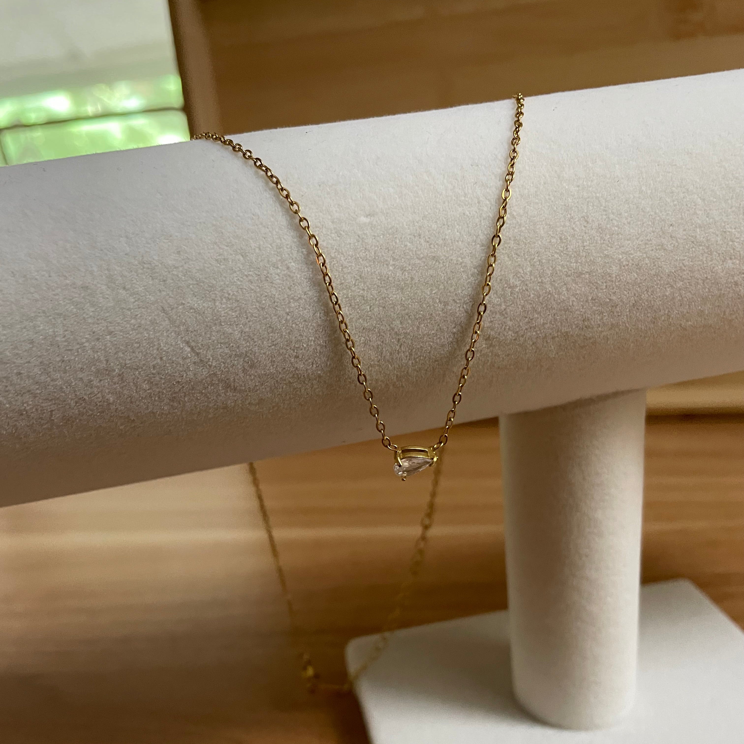 Gold bracelet on a mannequin arm against a wooden background
